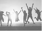 Team jumping on the beach by the sea at sunset
